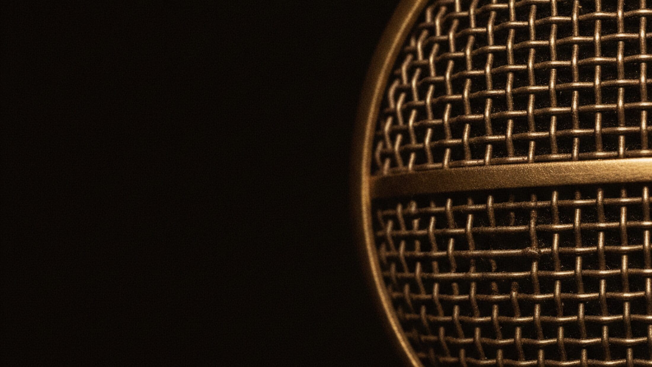 Macro of a vintage microphone grille under warm stage light