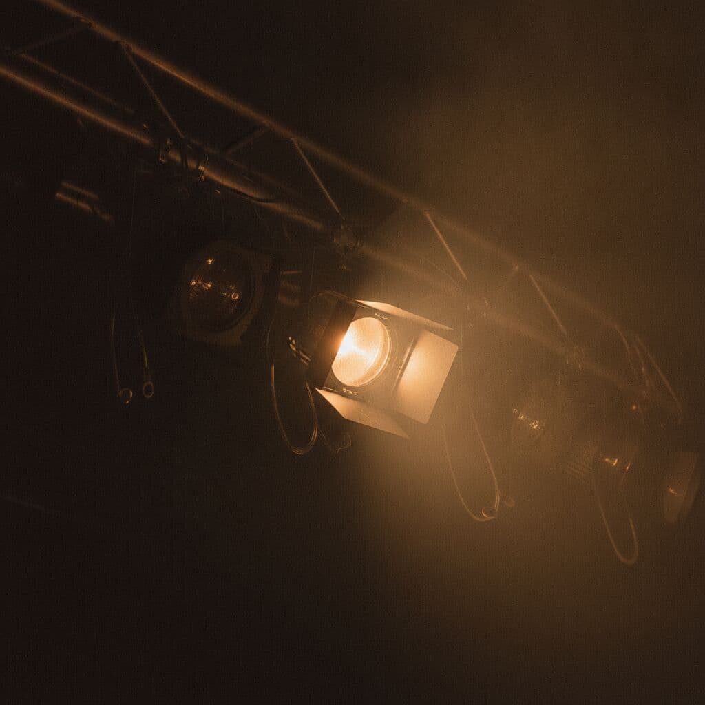 Stage lights cutting through haze above the crowd